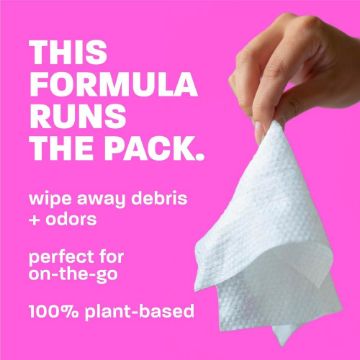 Hand holding a white wipe against a pink background with text about the product's uses and benefits.