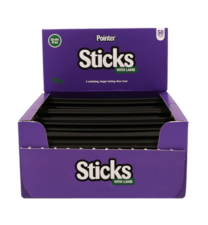 A purple box of Pointer Sticks With Lamb dog chews, shown open with multiple black sticks visible inside. The packaging features the Pointer brand logo and a green 'grain free' badge.