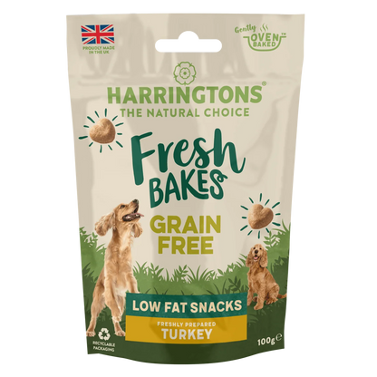 A 100g stand-up pouch of Harringtons Fresh Bakes Grain Free Low Fat Snacks, Freshly Prepared Turkey, for dogs. The packaging features a beige background with green and yellow text, illustrations of two golden retriever dogs, and a green bottom section.