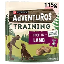 Purina Adventuros Training dog treats pouch for puppies, 115g, rich in lamb flavor, featuring a green and brown package design with illustrations of a dog and a person, and a clear window showing the treats inside.