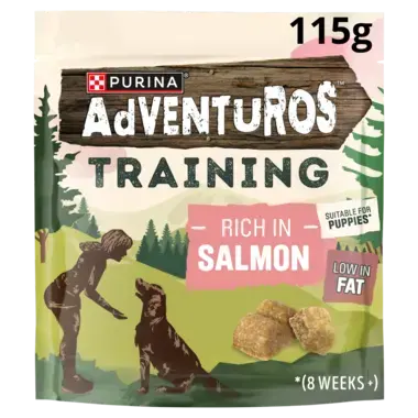 Purina Adventuros Training dog treats pouch, Rich in Salmon flavor, 115g. The packaging features a forest illustration with a silhouette of a person training a dog, salmon treats, and text indicating suitability for puppies and low fat content.